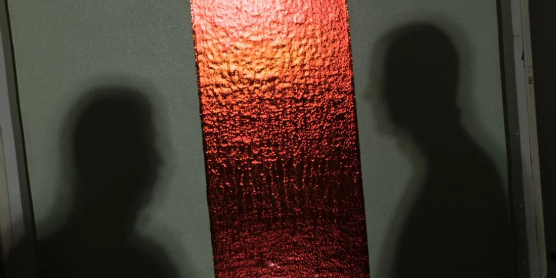 Deux ombres sur fond vert avec bande rouge centrale texturée.