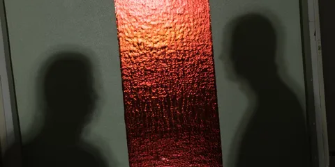 Deux ombres sur fond vert avec bande rouge centrale texturée.