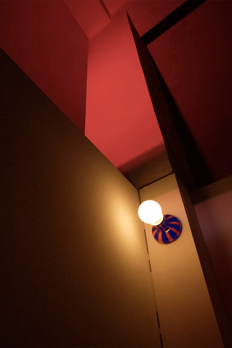 Lampe murale avec abat-jour rouge et lumière douce.