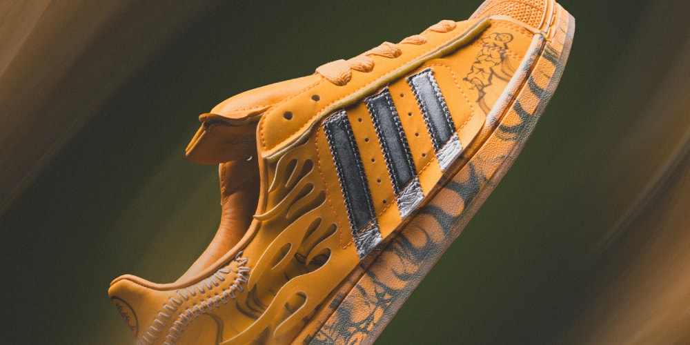 Chaussure orange, rayures noires et détails de flamme sur le côté, fond flou.