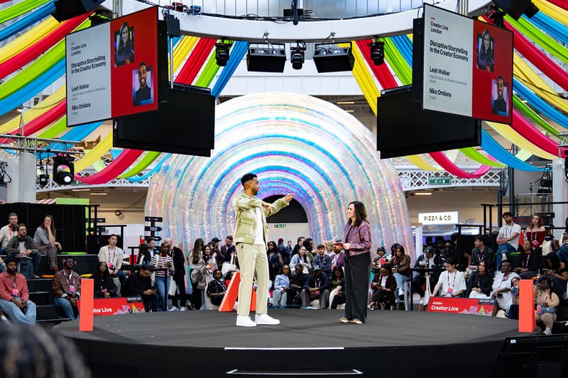 Deux personnes sur scène devant un public avec décor coloré en arrière-plan.