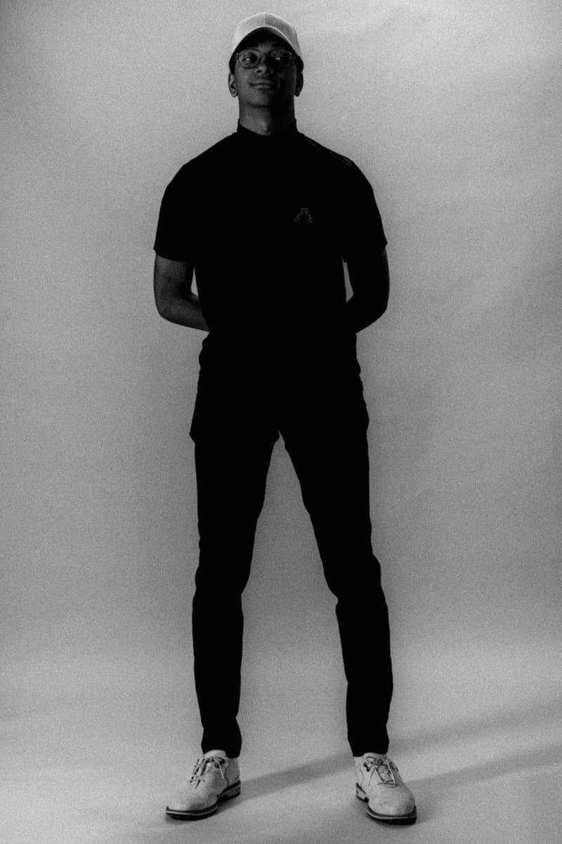 Homme debout en noir et blanc, portant casquette et lunettes.