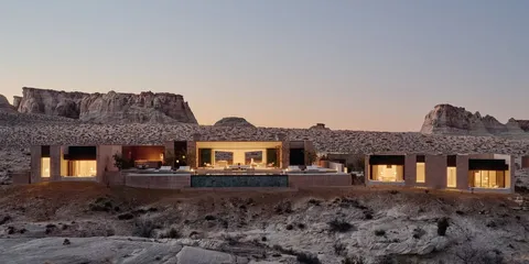 Maison moderne dans un désert avec des collines en arrière-plan.