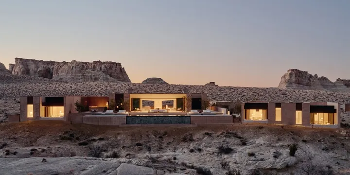 Maison moderne dans un désert avec des collines en arrière-plan.
