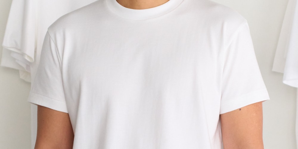 Personne portant un t-shirt blanc, vêtement simple et épuré.