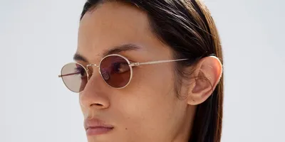 Personne portant des lunettes rondes avec des verres teintés.