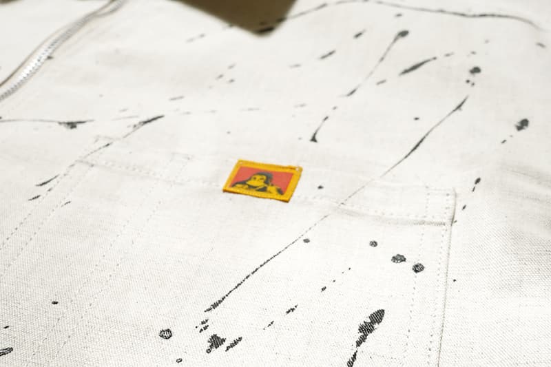 Poche de vêtement beige avec taches noires et étiquette jaune.