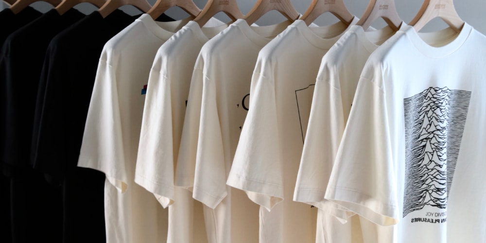 Des t-shirts noirs et blancs accrochés sur des cintres.