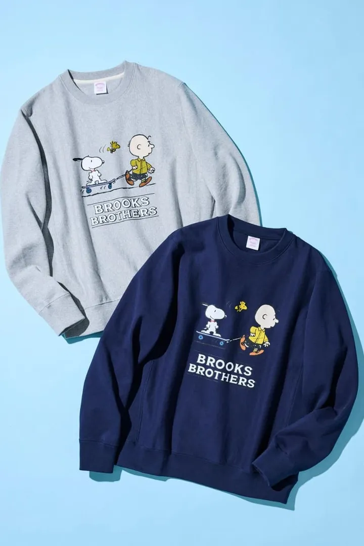 Deux sweat-shirts Peanuts Brooks Brothers sur fond bleu.