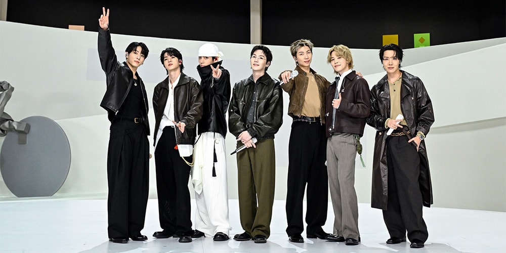 Groupe de sept hommes en vestes, posant sur scène moderne.