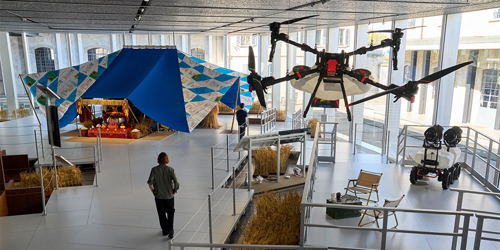Exposition intérieure avec drone suspendu et tente colorée