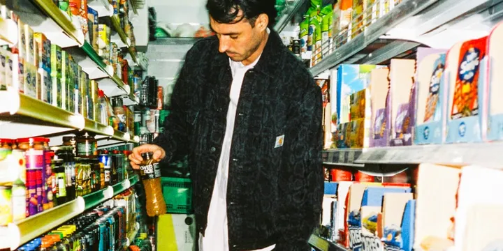 Homme dans une épicerie, tenant une bouteille sur l'étagère.