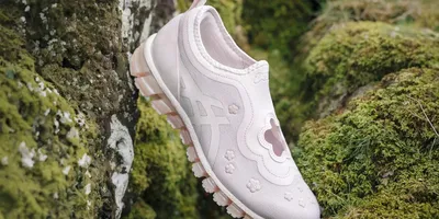 Chaussure rose avec motif floral sur fond de mousse verte.