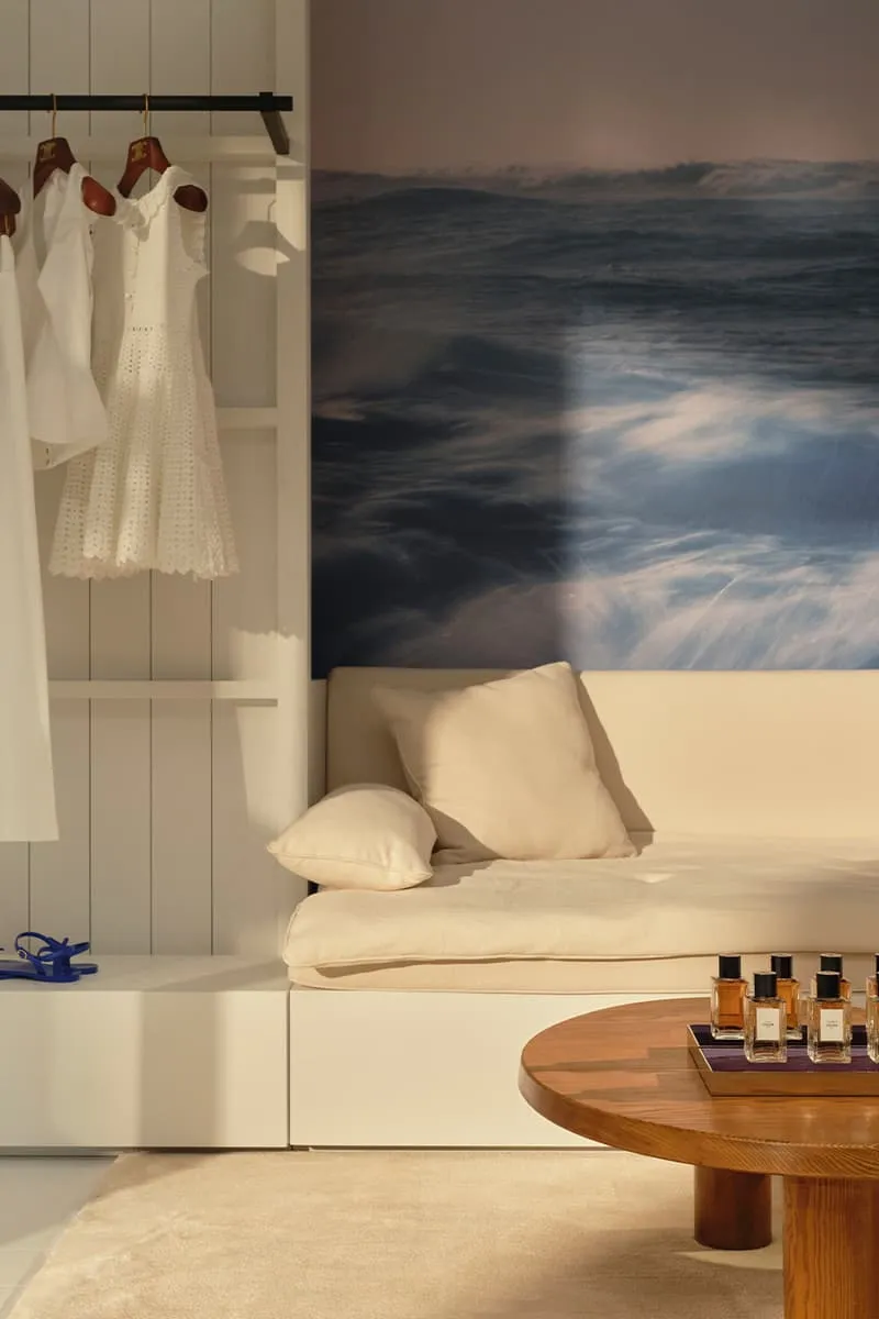 Intérieur chic avec vêtement blanc, canapé beige, table ronde et parfum.