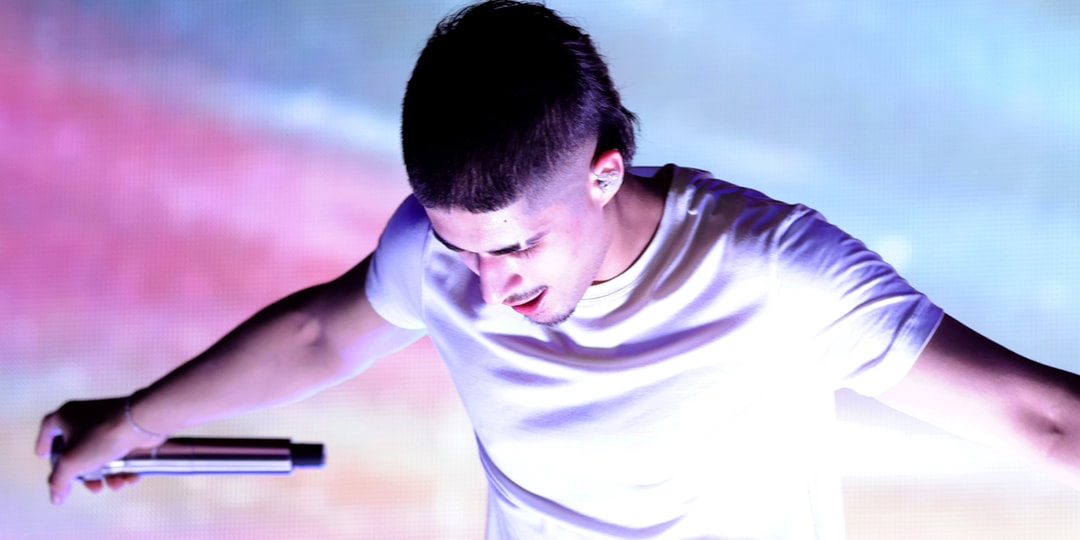 Homme tenant un micro sur scène, éclairage coloré et vif.