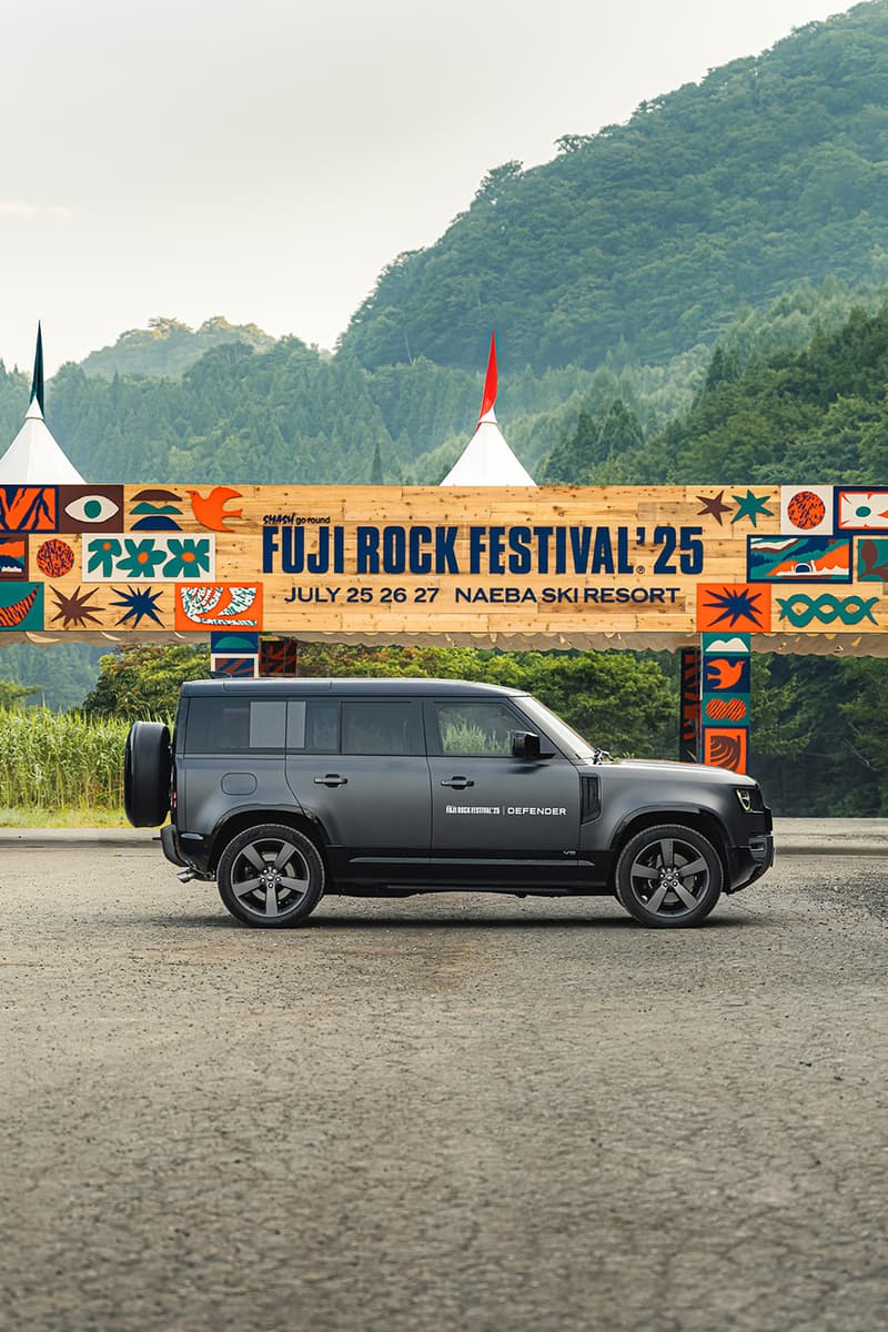 Voiture devant panneau Fuji Rock Festival 2025, montagnes en arrière-plan.
