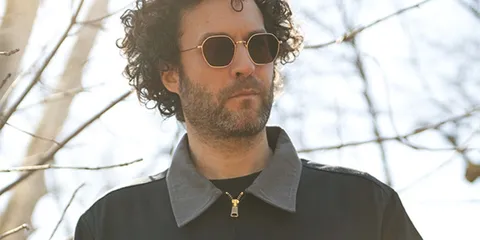 Homme portant des lunettes de soleil et veste sombre, jour ensoleillé