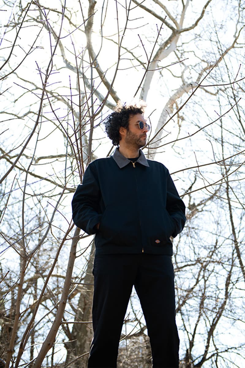 Homme avec lunettes de soleil dans un parc en hiver, branches nues tout autour.