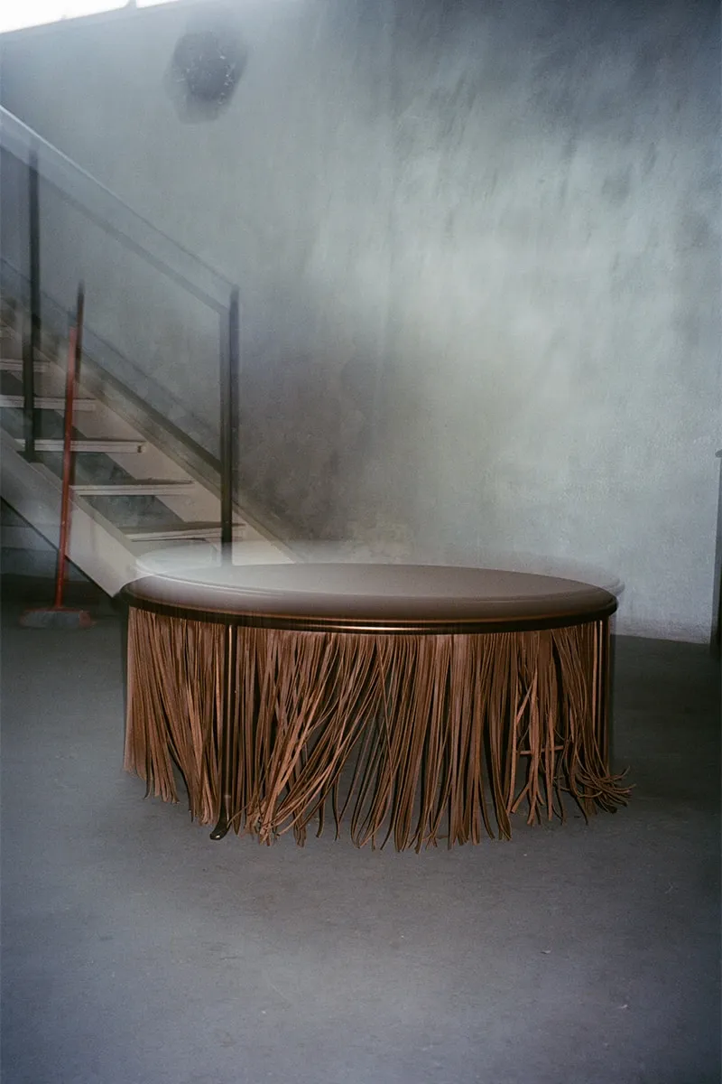 Table ronde avec franges marron dans un espace industriel.