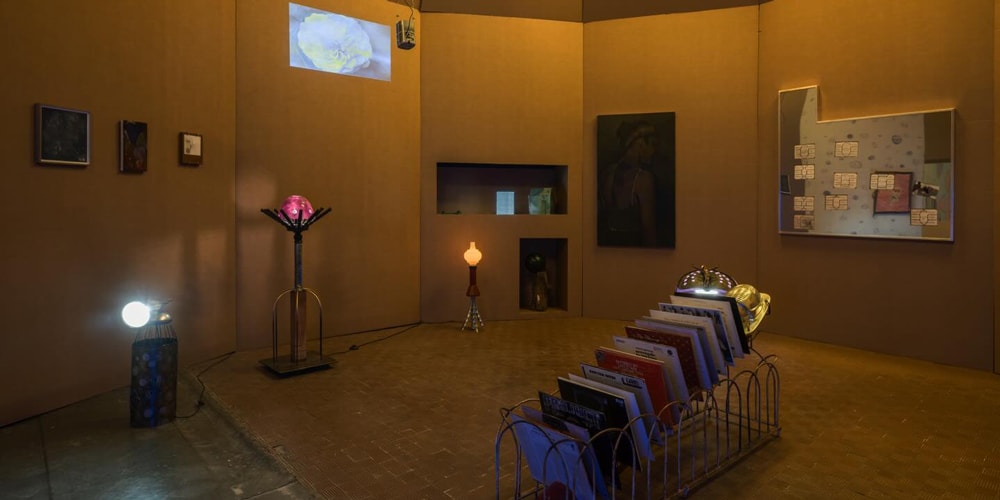 Exposition d'art avec lumières et peintures sur des murs en carton.