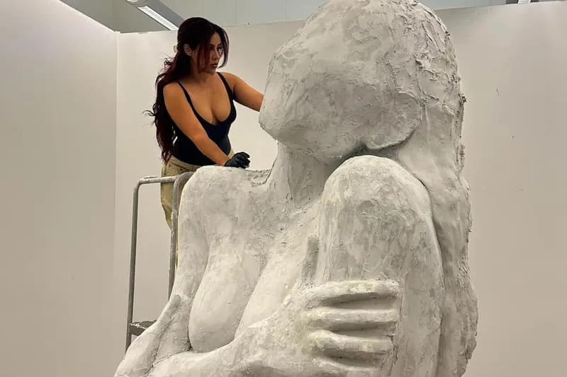Femme sculptant une statue en argile dans un atelier.
