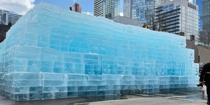 Structure de blocs de glace devant des immeubles urbains modernes.