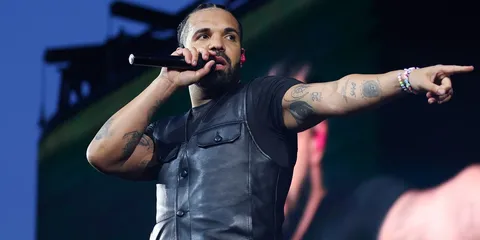 Chanteur sur scène avec micro, portant un gilet noir.