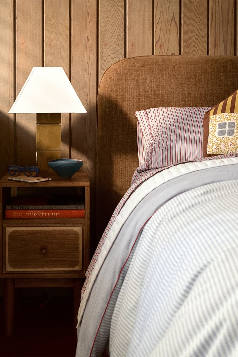 Chambre avec lampe sur table de chevet et lit aux draps rayés