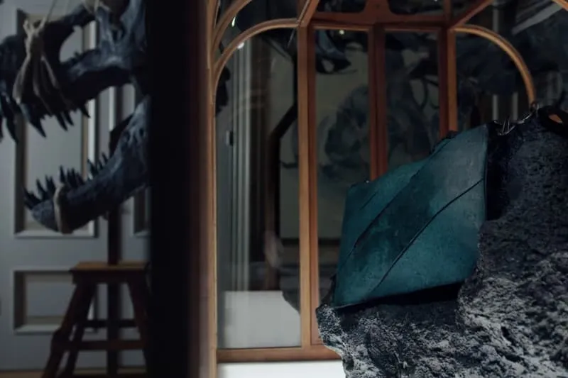 Installation artistique avec un sac vert et une sculpture de dragon.