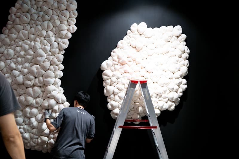 Un homme travaille sur une installation d'art blanc avec une échelle.