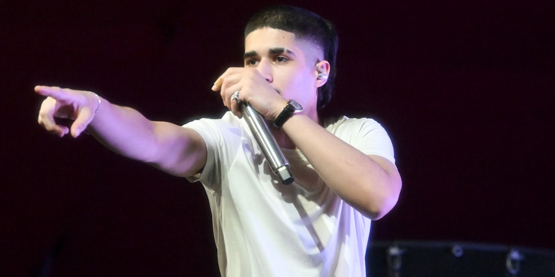 Chanteur en t-shirt blanc avec micro sur scène.