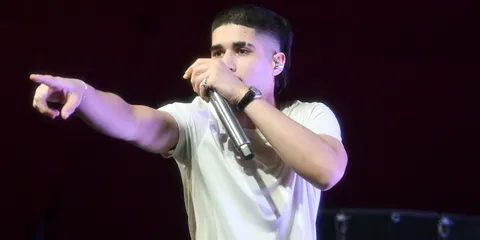 Chanteur en t-shirt blanc avec micro sur scène.