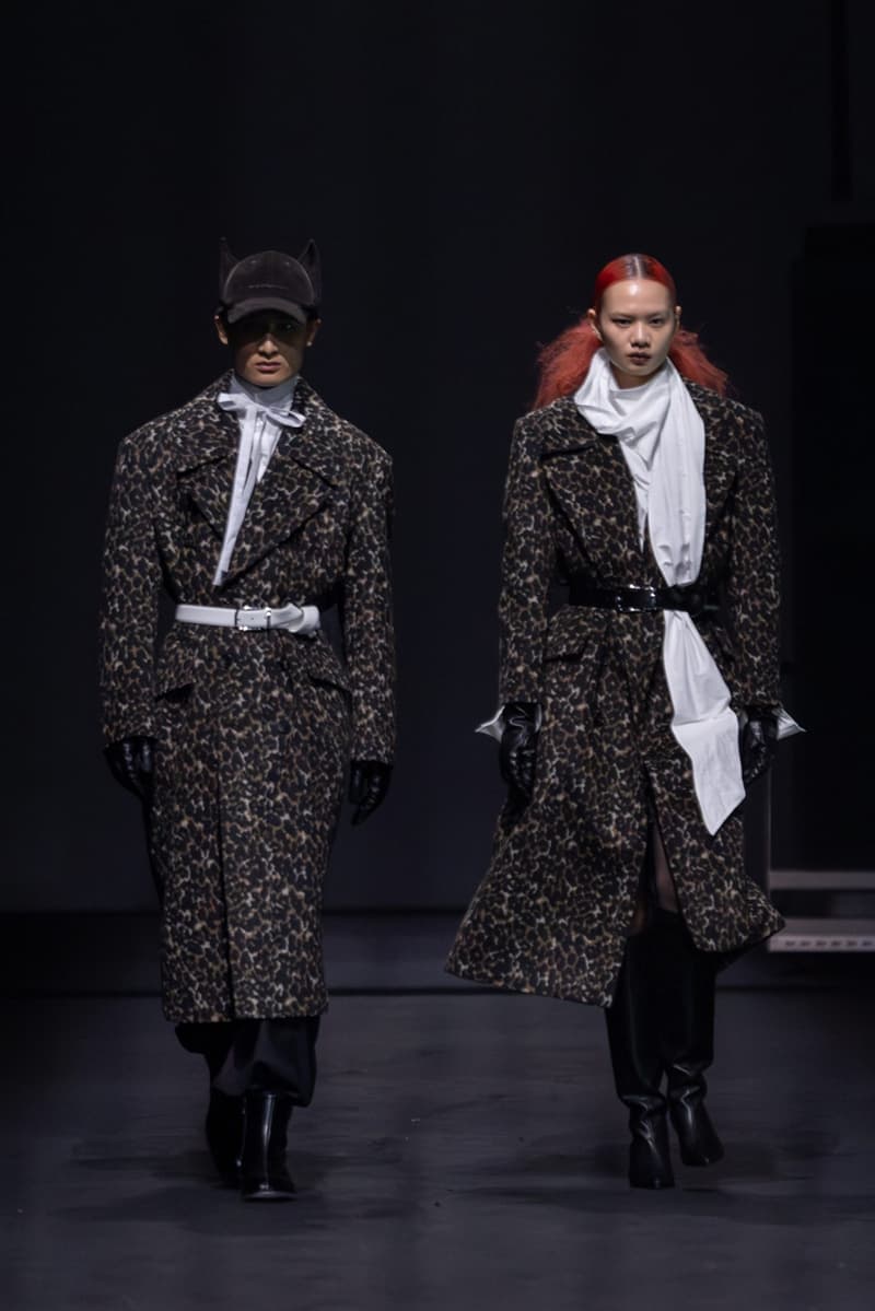 Deux mannequins défilent en manteaux léopard et gants noirs.