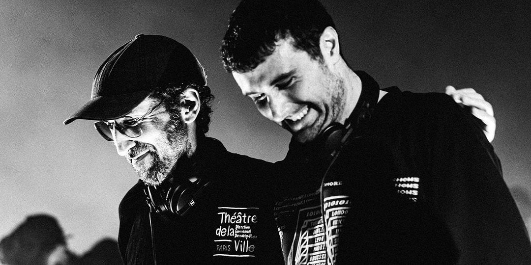 Deux hommes souriant sur scène avec écouteurs autour du cou.