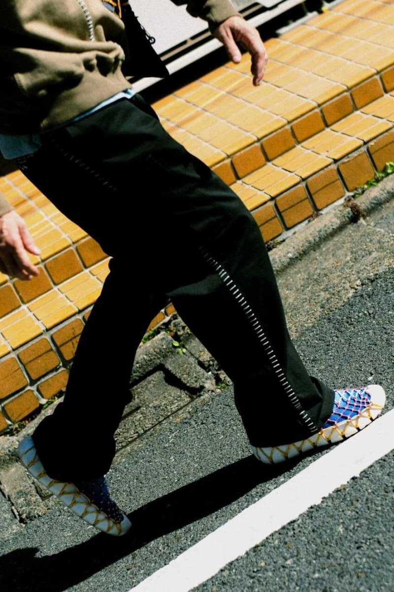 Personne marchant sur un trottoir avec des chaussures uniques et un pantalon noir.