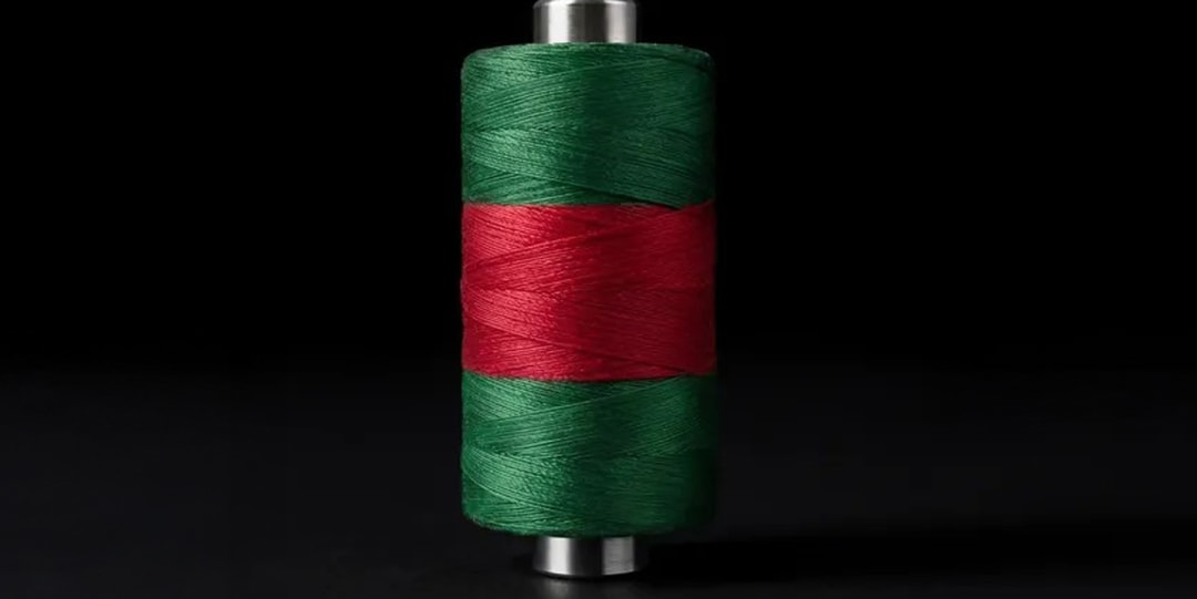 Bobine de fil vert et rouge sur fond noir.