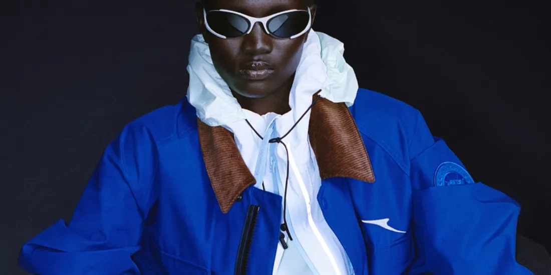 Personne portant des lunettes et une veste bleue sur fond sombre.