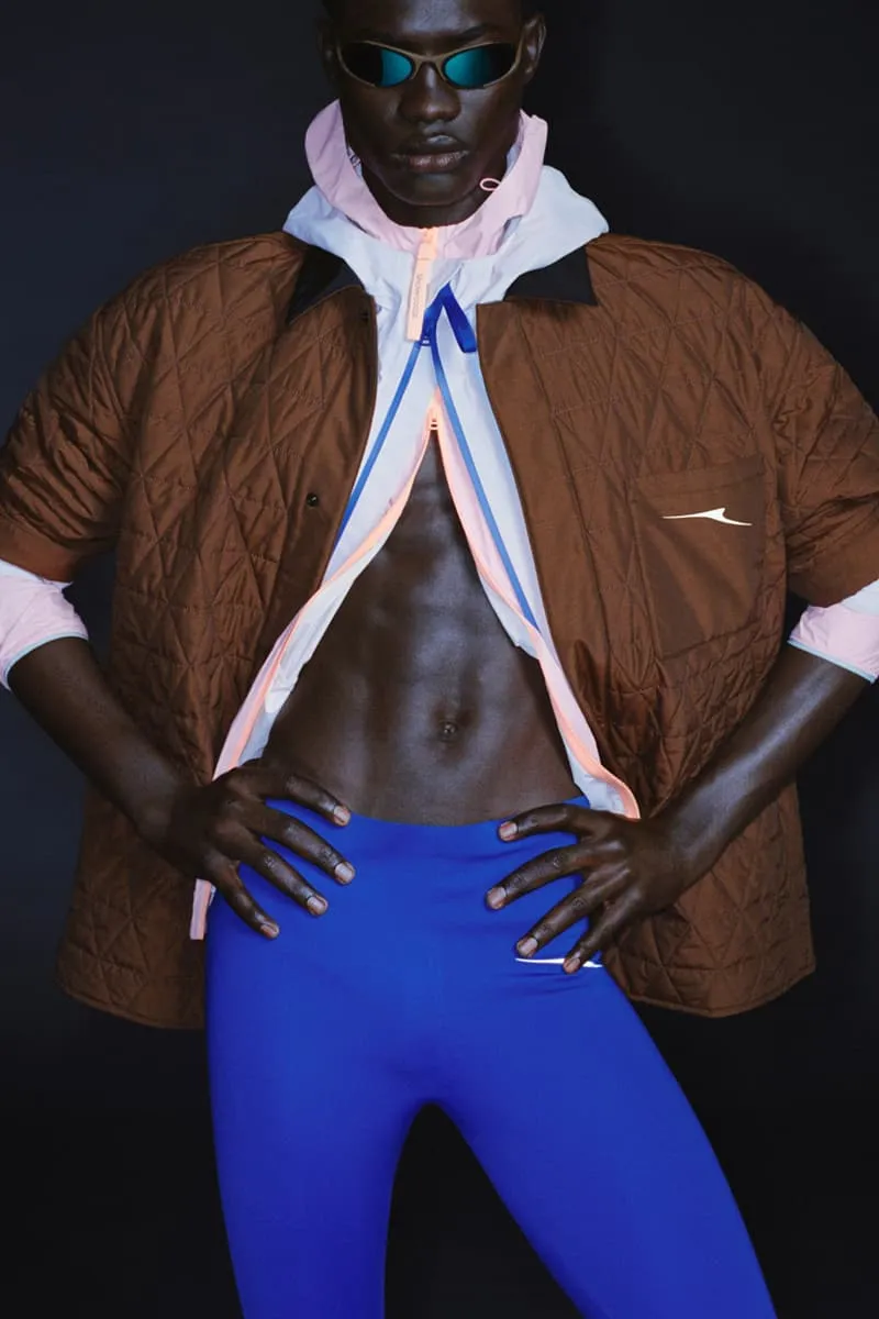 Personne avec des lunettes de soleil, veste matelassée et leggings bleus sur fond noir.