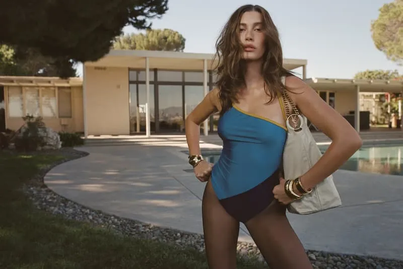 Femme en maillot de bain devant une maison moderne avec piscine.