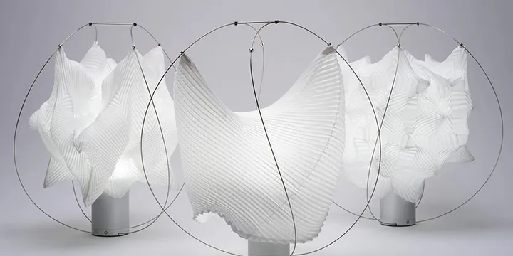 Lampes sculpturales blanches avec motifs plissés et cadres métalliques.