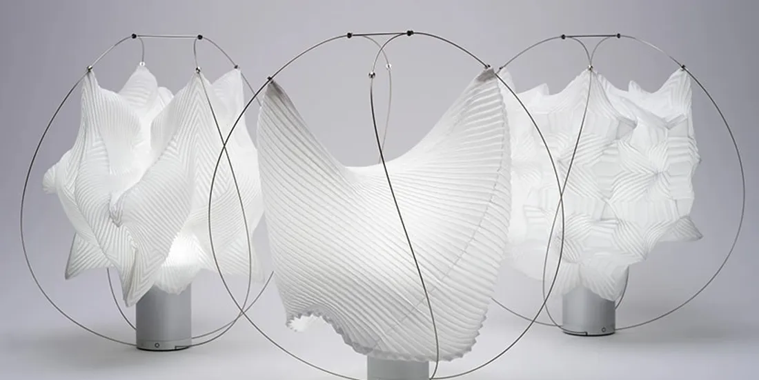 Lampes sculpturales blanches avec motifs plissés et cadres métalliques.