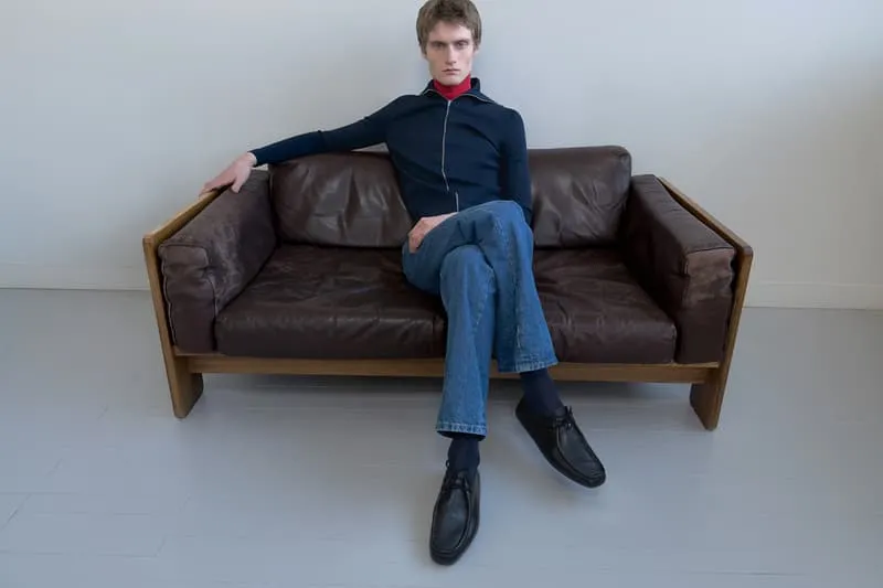 Homme assis sur un canapé en cuir marron, pose détendue.