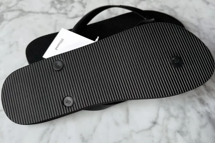 Sandale noire vue de dessous sur fond de marbre.