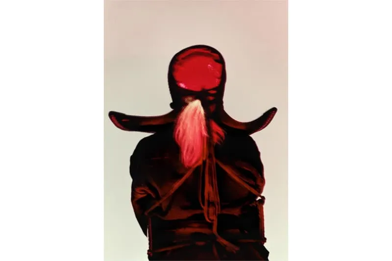 Personnage en capuche et manteau rouges, dos à la caméra.