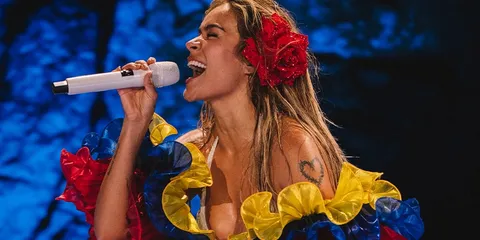 Chanteuse en costume coloré avec micro sur scène.