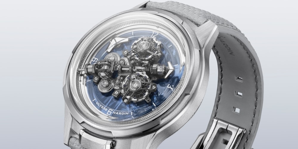 Montre argentée avec mécanisme visible et bracelet en cuir gris