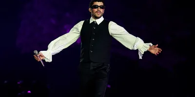 Personne en concert avec micro et tenue élégante, fond violet.