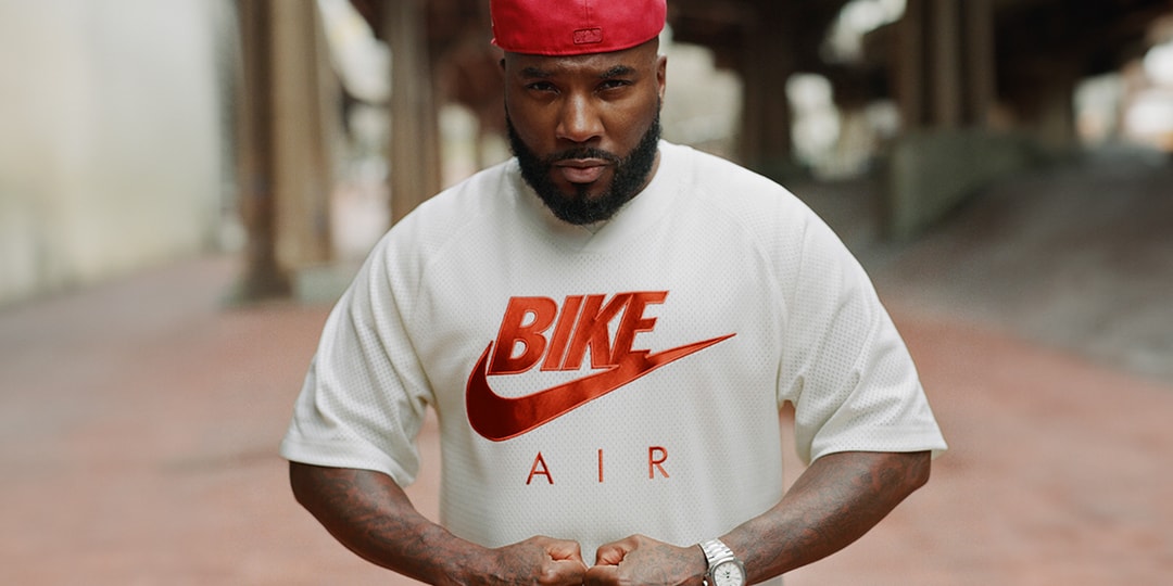 Homme avec t-shirt blanc et casquette rouge dans une rue urbaine.