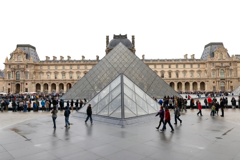 Pyramide du Louvre avec des visiteurs autour, ciel nuageux