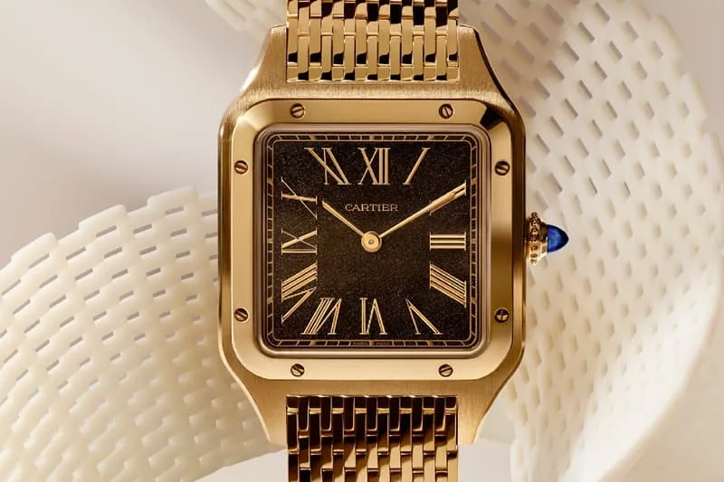 Montre Cartier dorée avec chiffres romains sur bracelet doré.